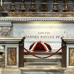 Wieniec z czerwonych róż na grobie Jana Pawła II. "Sanctus Ioannes Paulus PP. II" wyryte na marmurze.